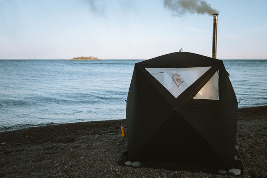 Portable North Shore Sauna tent set up outdoors with steam rising from the chimney.
