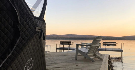 North Shore Nova Sauna Tent set up on a snowy backyard lawn with a plume of white smoke rising from the wood stove chimney.