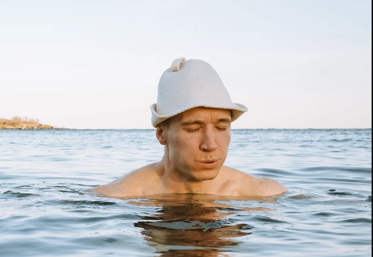 Portable sauna tent set up outdoors in nature with steam rising from the chimney