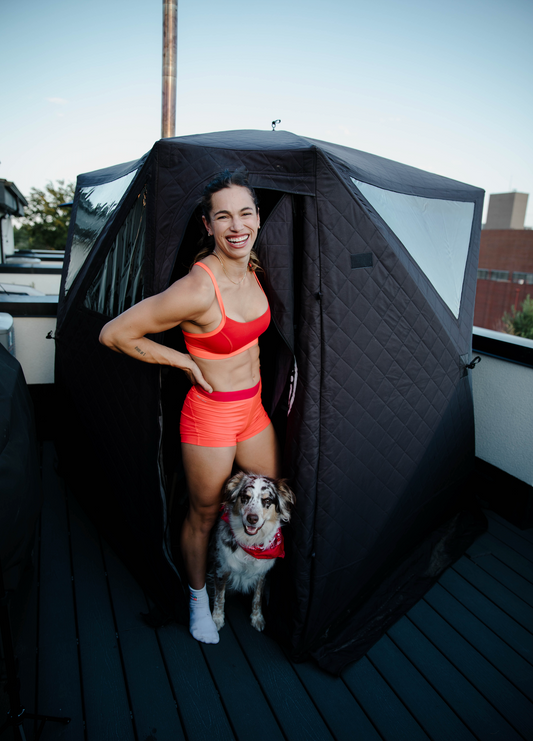 A fitness model stands outside of her North Shore Sauna portable sauna tent.
